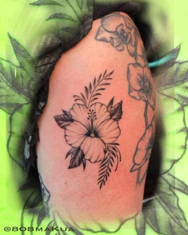 Black and grey floral tattoo on the upper arm.