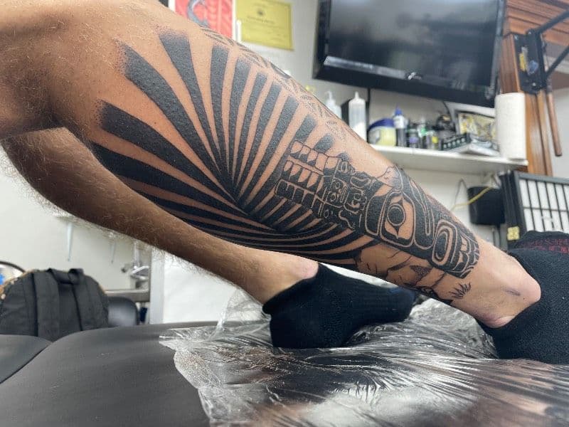 A calf tattoo with bold black geometric patterns.