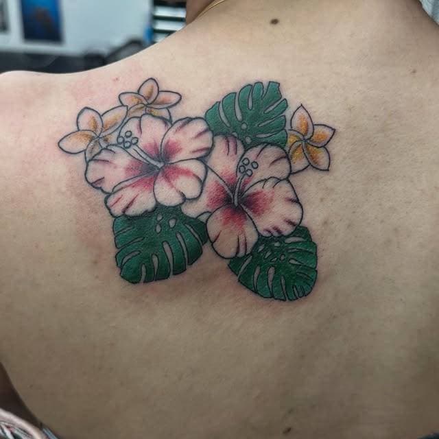 Colorful hibiscus and leaves tattoo on the upper back.